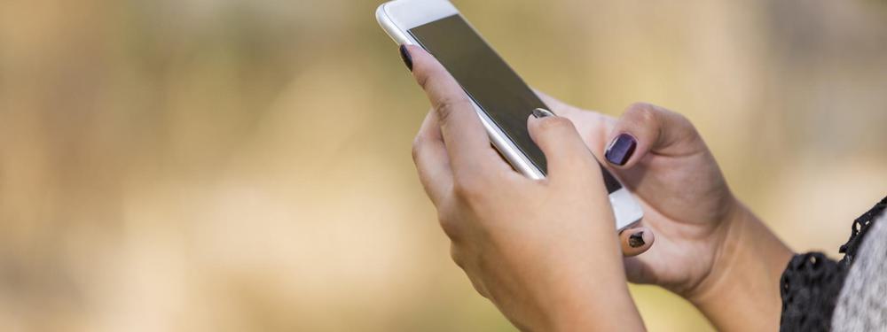 Womans hands with purple nails holding mobile phone